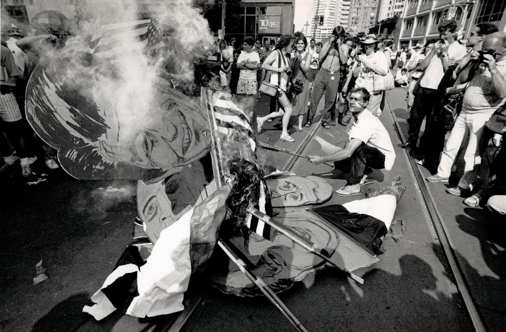 At right, a U.S. flag and posters of the Economic Summit leaders go up in flames on University Ave. yesterday when police arrested 137 protesters who tried to scale barriers