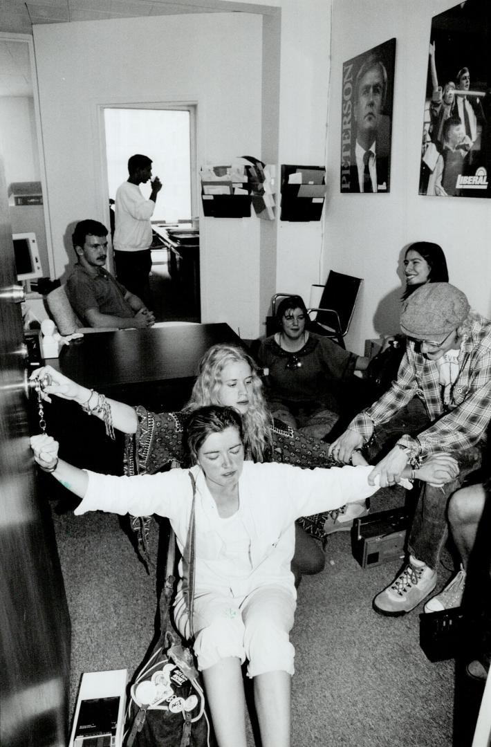 Locked in Battle, Anti-logging protesters handcuffed themselves to the door and each other yesterday at the Liberal party headquarters on St. Mary St.(...)