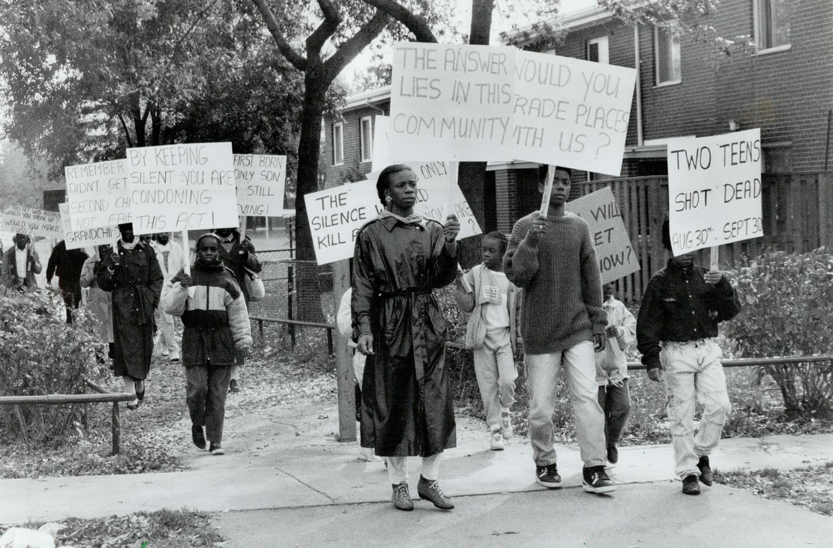 Silent protest: Members of Bruce Olayinka's family march yesterday through the housing complex where he was killed