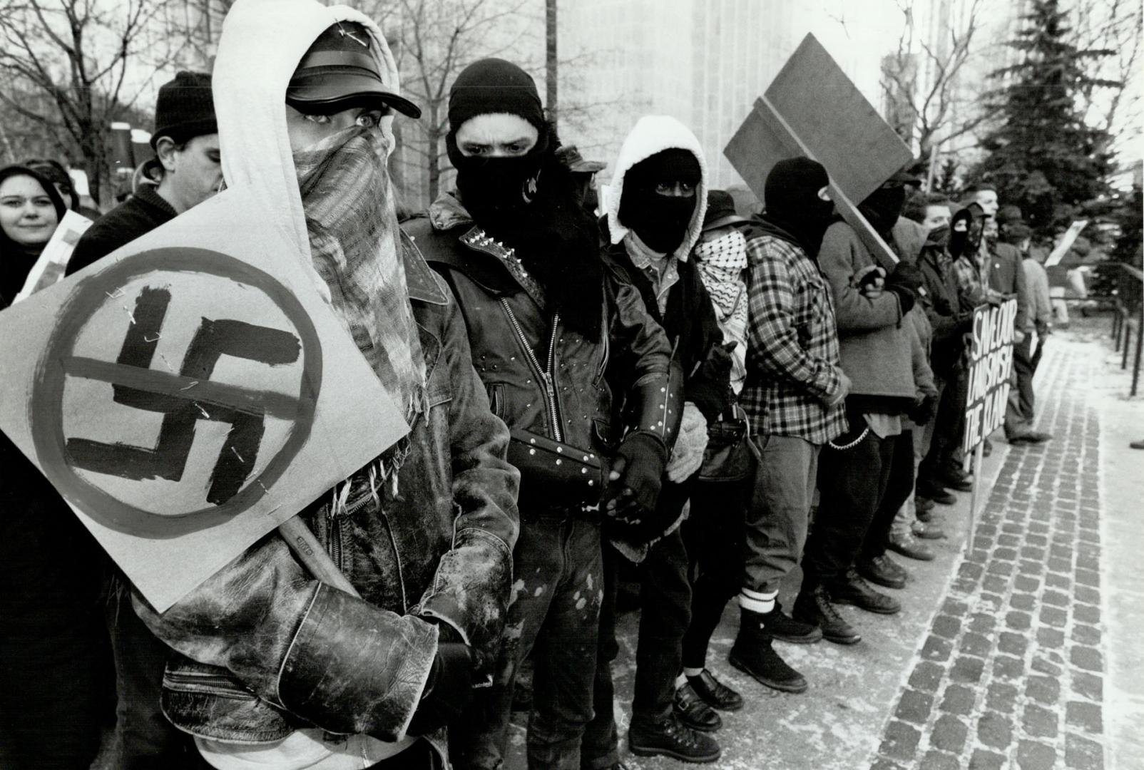 Human barricade: Hooded protesters line up with anti-nazi signs in bid to bar Heritage Front members from entering courthouse