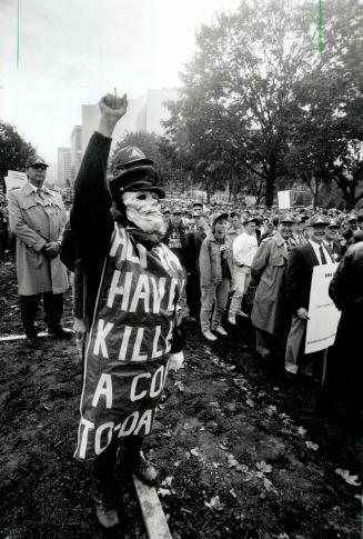 Macabre message: A demonstrator, wearing a skeleton mask and a sign claiming provincial laws will lead to more police deaths, waves in support of officers