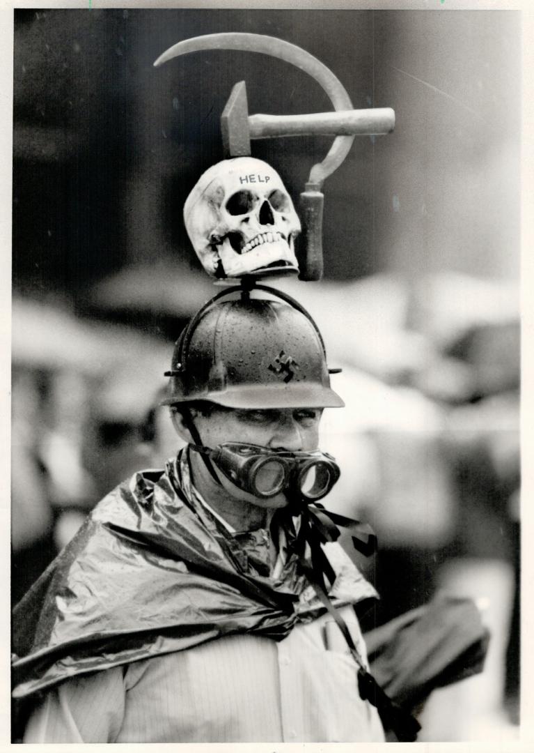 Graphic protest: A man who said he was a native of Latvia makes his protest with graphic headgear at a rally at Nathan Phillips Square yesterday against Communist oppression