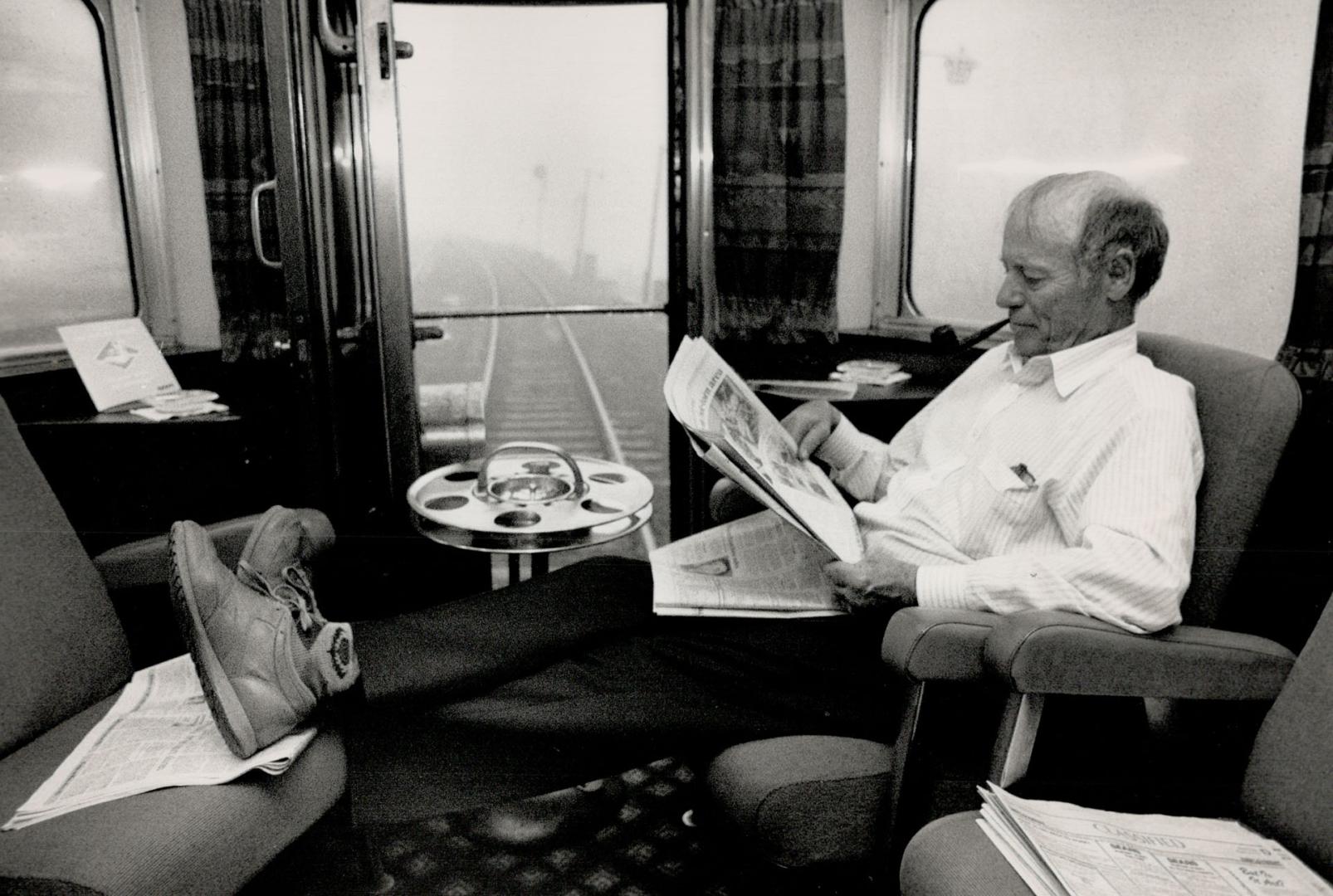 Rail Relaxation: Bob Macdonald of Burlington puts his feet up and settles down to read his newspaper as Via Rail's Transcontinental train rolls through Muskoka