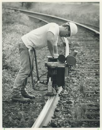 The right side of the tracks, CN Rail employee Chris Ramsey bellies up to a profile grinder to finish off the newly installed rail tracks near Pottery(...)