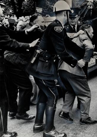 In police hands is one of eight men arrested yersterday after a hate-filled riot against suspected Nazis by a milling mob in Toronto's downtown Allan Gardens