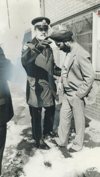 Shoeless in the snow, this worshipper at the Shromani Sikh temple tries unsuccessfully to convince a police officer to let him go back for his shoes after a brawl between factions on Sunday