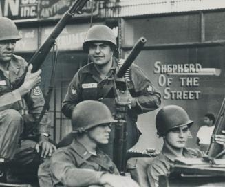 Sign in store window adds a touch of irony to the riot-torn streets of cleveland, Wary National Guardsmen in Jeep keep guns cocked, eyes peeled and their vehicle moving while on street patrol