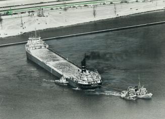 Straining at their towlines, tugs try in vain to pull the freighter George M