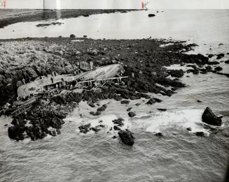 Gaunt skeleton of the Boston dragger Rainbow is shown on Yarmouth rocks where boat owner and two companions braved high seas in gallant rescue attempt(...)