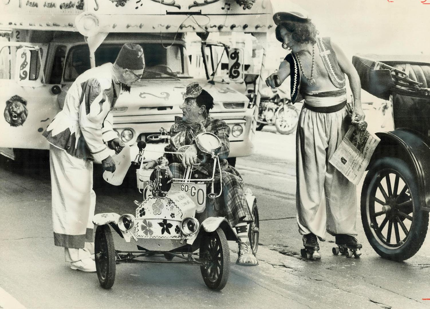 Out of gas at the very beginning of the seven-hour parade of Shriners today, a member of the Al Koran clown unit gets a fill-up from a fellow Shriner (...)