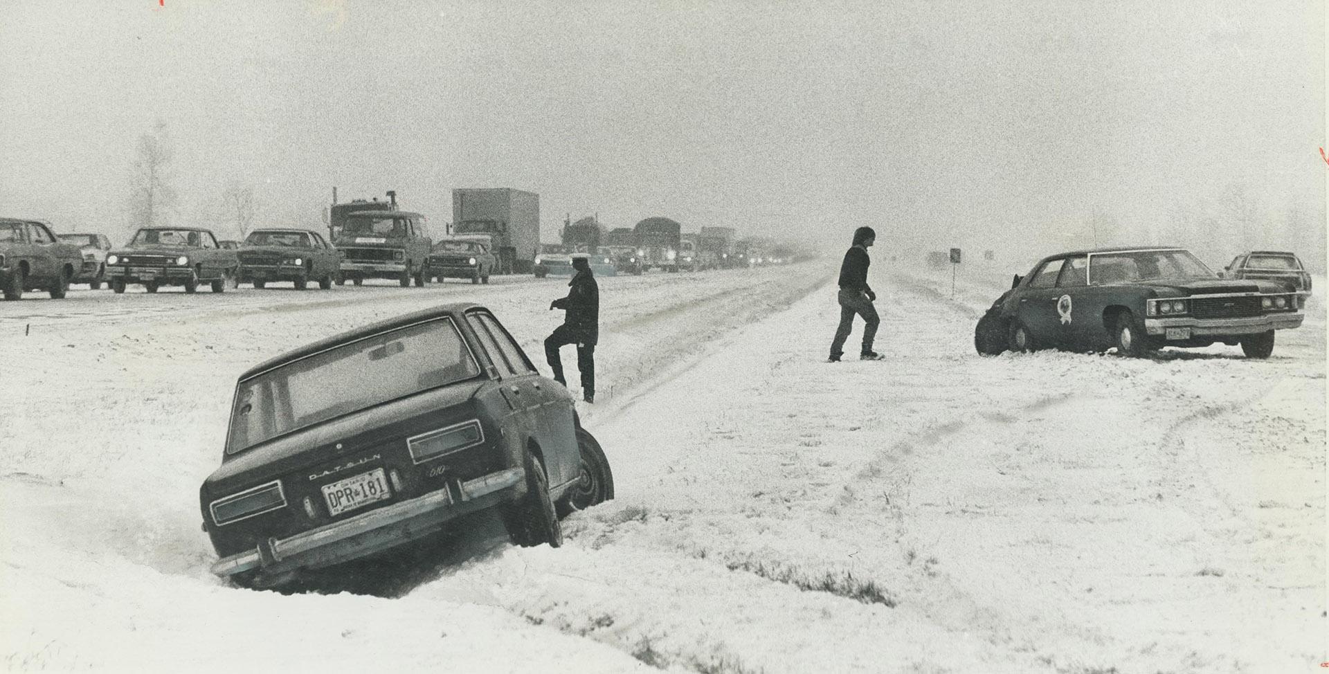 Cars are abandoned in the snow on Highway 401 at Trafalgar Rd