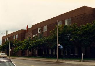 Image shows a three storey school building from the street side with a number of trees in front…