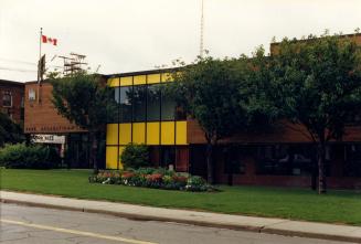 Image shows a two storey centre facing the street with a Canadian flag on the roof with some tr…