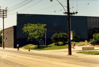 Image shows a street view with a recreation centre on one side. There are some trees and bushes…