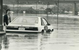 Riad Aboutarieh watches as tow truck operator Richard Creelman goes shoulder-deep in water to attach line to his car on Bayview