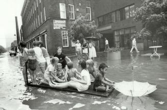 Kids sail an impromptu raft along The Esplanade near Berkeley St