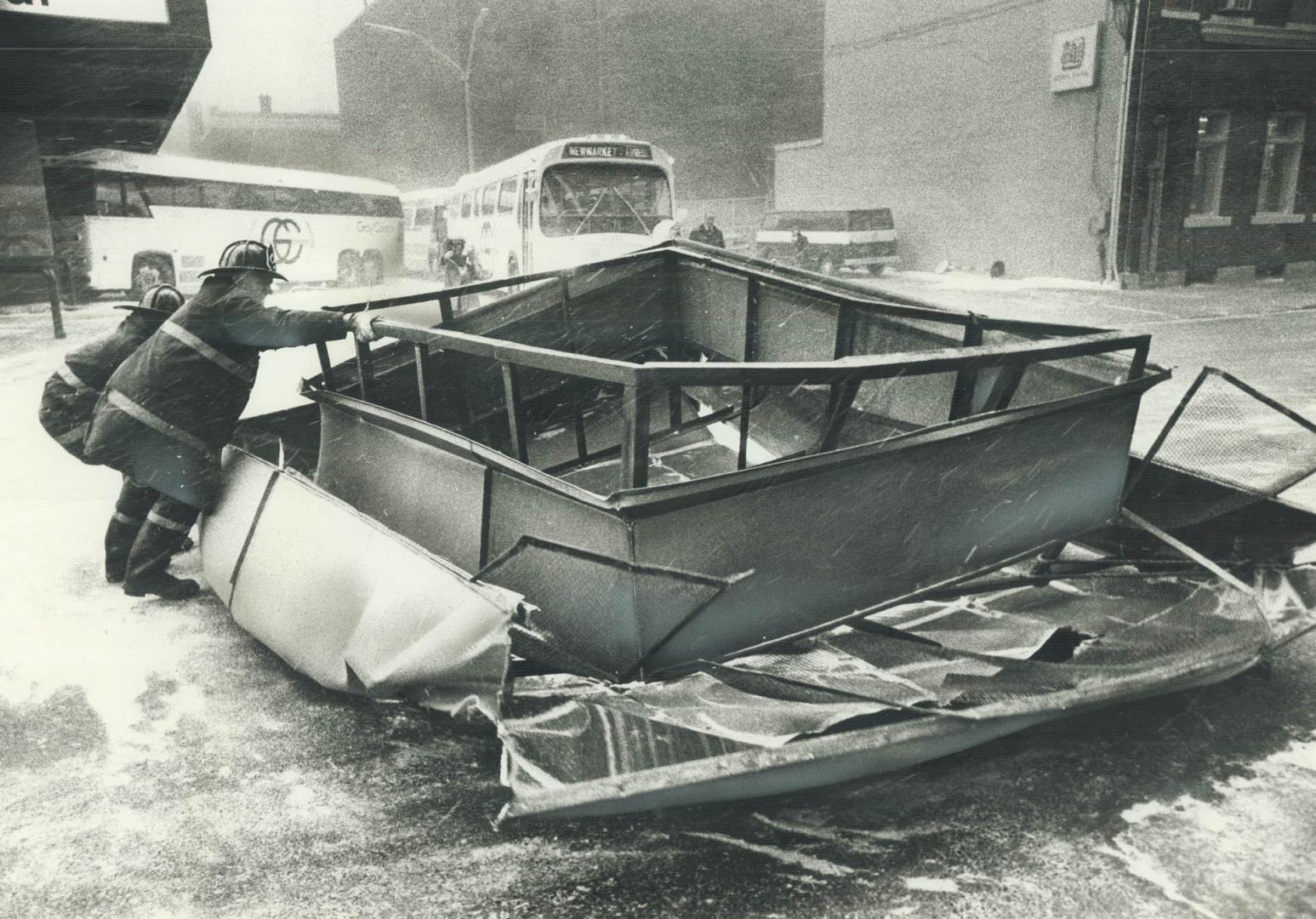 Firefighters push a large metal roof cap off the roadway after it was blown off by hurricane-force winds at Chestnut and Dundas Sts