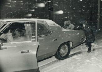 Helping hand: Passersby give unidentified driver a push on one of Metro's slippery side streets last night after high winds and snow turned roads into skating rinks