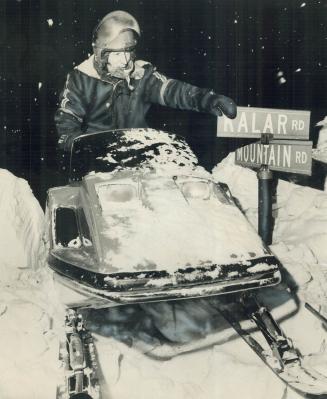 Niagara falls street sign barely sticks out of a snowdrift as snowmobiler Ralph Terrio checks his bearings last night while assisting in looking for m(...)