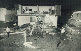 Rick Swiech sifts through the remains of his shattered semi-detached Woodstock home while his father Joe holds flashlight. Woman at left is Sharon Breton, who lives in the other half of the house