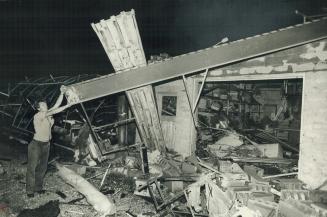 Grant Byers holds beam of florist shop demolished by a violent tornado that raced through woodstock yesterday