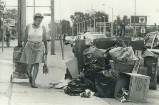 North York resident Elizabeth Kedves detours around a garbage pile that almost buries a Yonge St