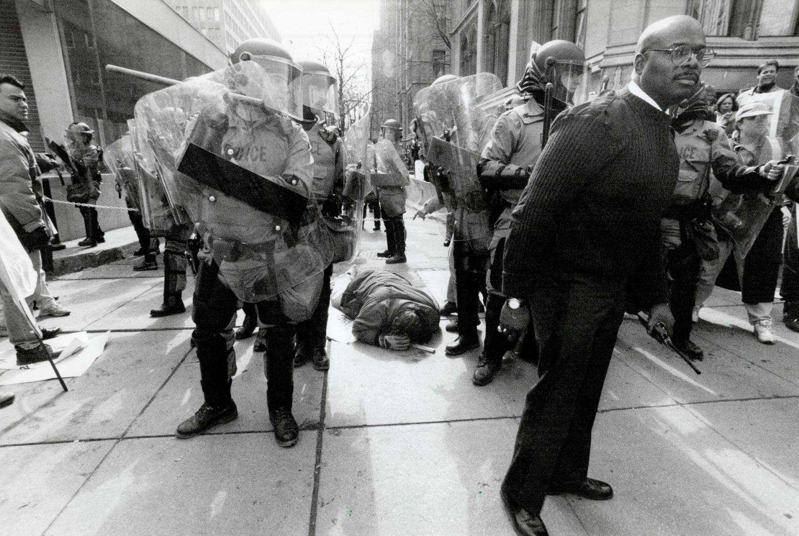 Out cold: Steve Giles, a probation and parole officer, lies unconscious yesterday outside the Whitney Building after being clubbed by OPP riot police during OPSEU demonstration at Queen's Park