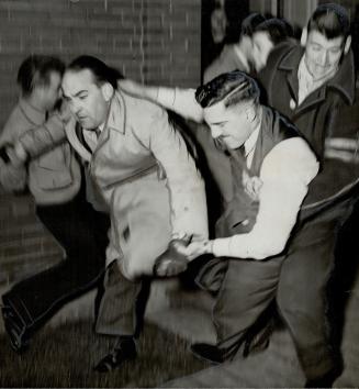 Man in coast, is being rushed out by a shirt-sleeved worker while a third man tries to stop him during the melee in Leaside. Disorder broke out when A.F. of L. Workers tried to pass C.I.O. pickets