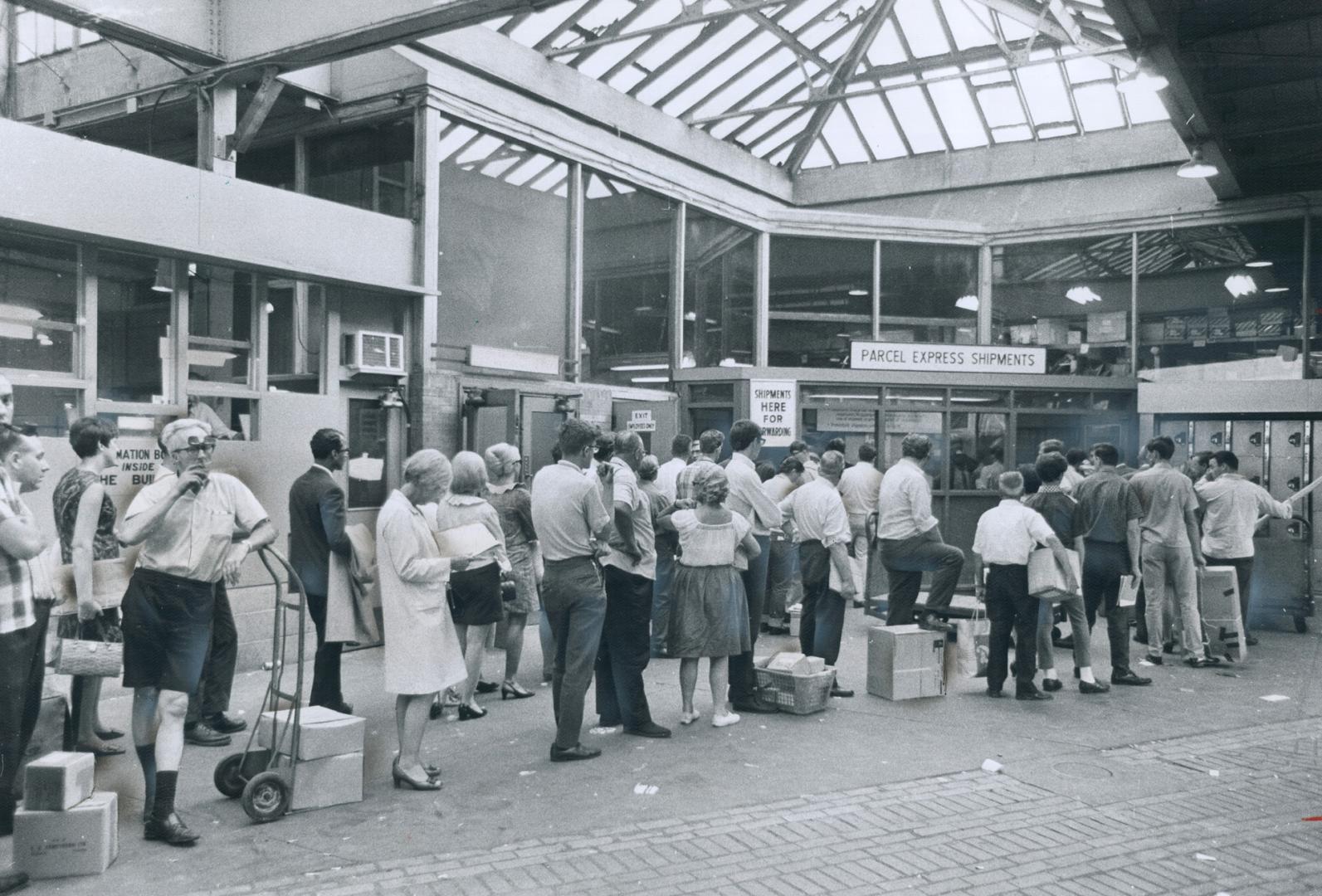 Getting their mail away despite the postal strike, people line up patiently in front of express window at bus terminal on Bay St., some of them using (...)