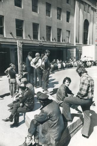 While a fire alarm rings, inside postal workers sit outside the Bay St