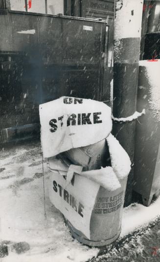 Discarded picket signs overflow a street trash basket outside the Post Office building at Bay St