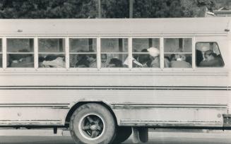 Replacement workers keep their heads down as they are bused past striking postal workers and into the South Central plant on Eastern Ave