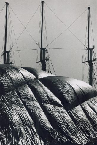 Sugar mountain, The three masts of the tall ship The Empire Sandy are silhouetted behind tonnes fo raw sugar covered by plastic at Redpath Industries (...)