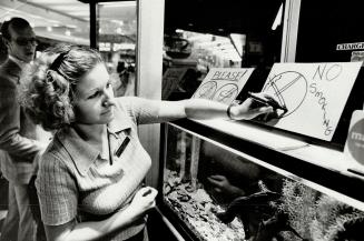 Smoke shop attendant puts up No Smoking sign in shop Oct