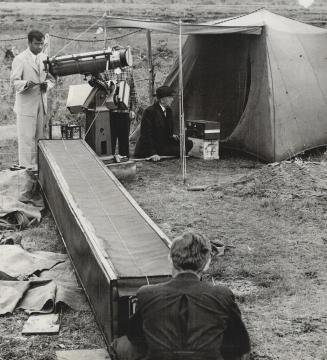 The 20-foot camera with the telescope at the far end is seen here while in the foreground is the photographer with plates. This was the main eclipse-catching camera