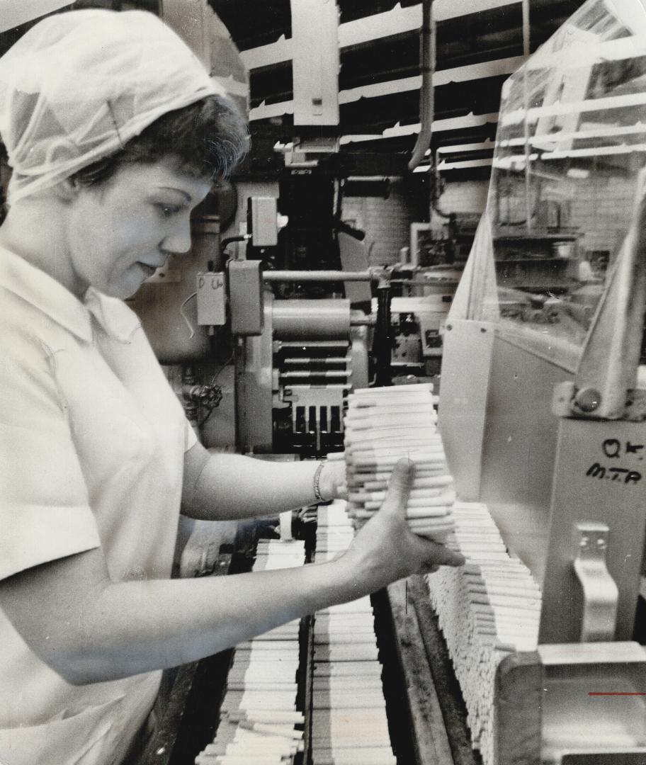 By the thousands and millions, fags pour out from one of Benson and Hedges cigarette-making machines