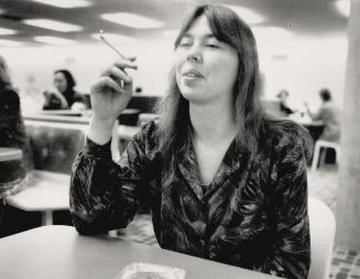 Refuse to quit: Shivering patients, left, smoke outside Toronto East General Hospital last March, above, Toronto employee Elizabeth Dodd takes a break in cafeteria