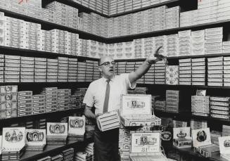 Reginald Fowler among his cigars, He gives them tobacconist's loving care