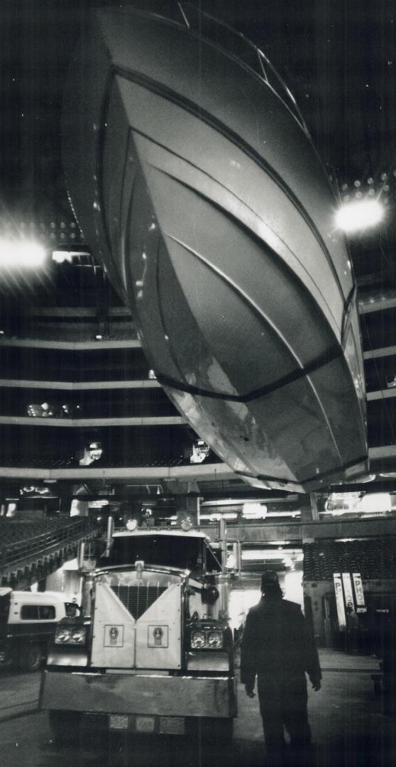 Flying in the Skydome, A worker is dwarfed by the hull of an overhanging vessel from a Mississauga marina at the International Power Boat Show that opens today at the SkyDome