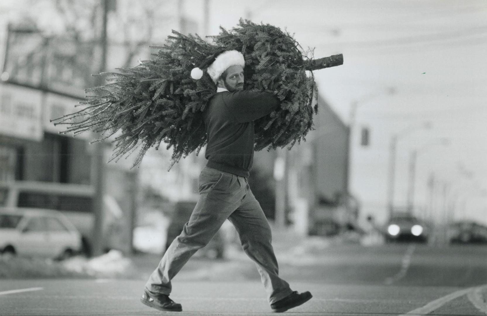 Spruced up in a Santa hat, Randy Klippenstein eyes the traffic while crossing Dundas St