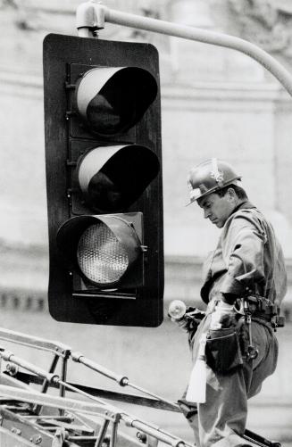 Pat Lloyd of Guild Electric, changes a bulb in a light at the corner of Lakeshore Blvd