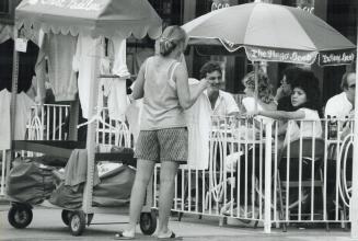 Shopping in comfort: This enterprising young woman takes her souvenir T-shirt stand right to the customers at an outdoor restaurant on Yonge St