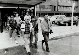 Facing the axe: A de Havilland worker, leaving the Downsview plant yesterday with fellow employees, reacts with a thumbs-down to news of 1,300 layoffs