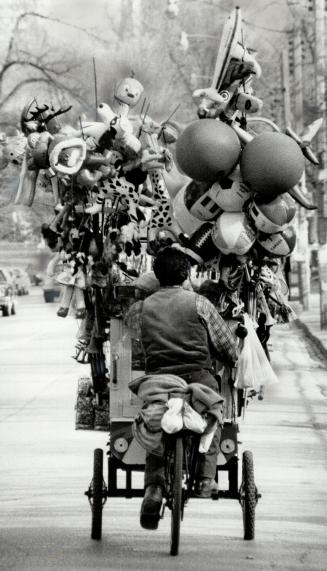 Watch where you're going: The recent warmer weather has brought out signs of summer, like this balloon and popcorn vendor who was spotted pedding his wares past Queen's Park yesterday