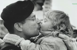 Dads Ahoy: A little lad, above left, scans the horizon for his father while a young girl, right, bestows a welcoming kiss on hers