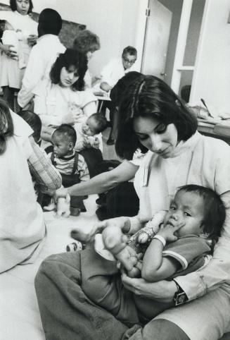 Leslie Green looks after 2 year old Dang The Ngee Dung Maria in amongst other orphans