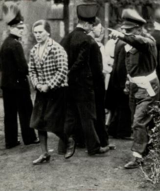 This woman laughed when she had seen the film of the Belsen and Buchenwold brutalities once, so a British officer orders her back into the theatre for a second view of horrors