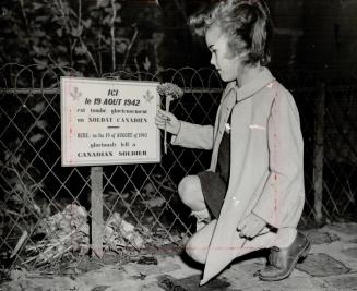 Volle Christiane placing a flower on the spot where one of our men fell at Dieppe, Aug. 19, 1942