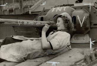 Adding the finishing touch to the Covenanter tank she helped to make, this young war worker is seen chalking up a bit of inspiration on the tank's gun and mounting