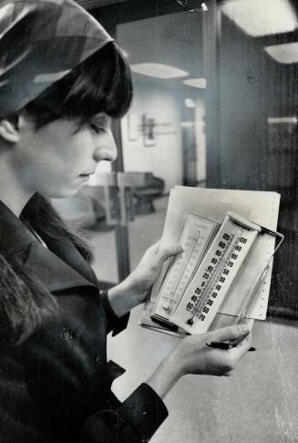 Star Staff Writer, Mary Janigan checks her thermometers in City Hall yesterday and finds the temperature well above the 68 to 70 degrees called for in(...)